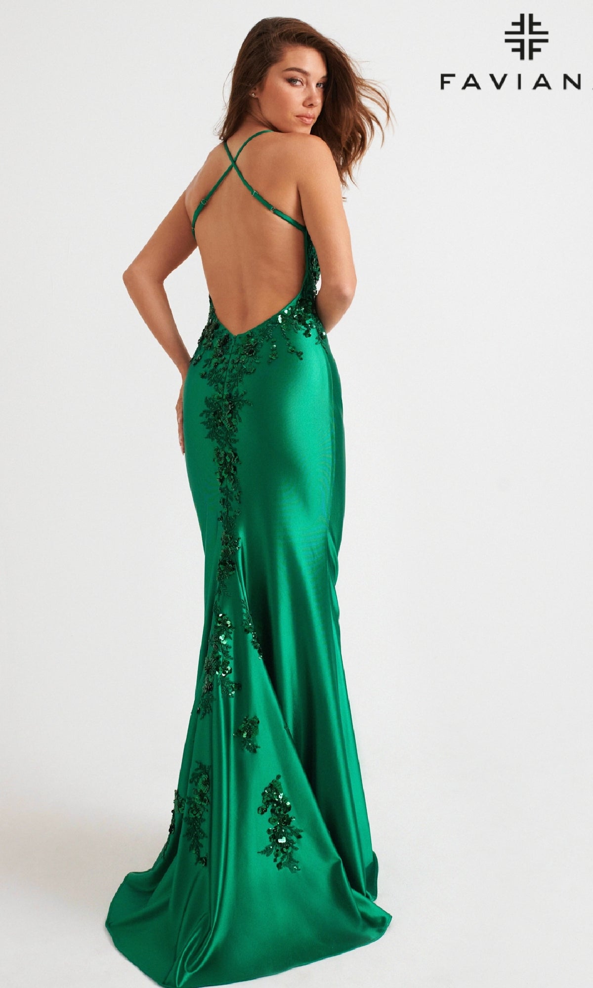 A woman models the Faviana 11247, a green floor-length prom dress with sequin embellishments. The backless gown has thin crisscross straps, a fitted silhouette, and the Faviana logo shown in the corner.